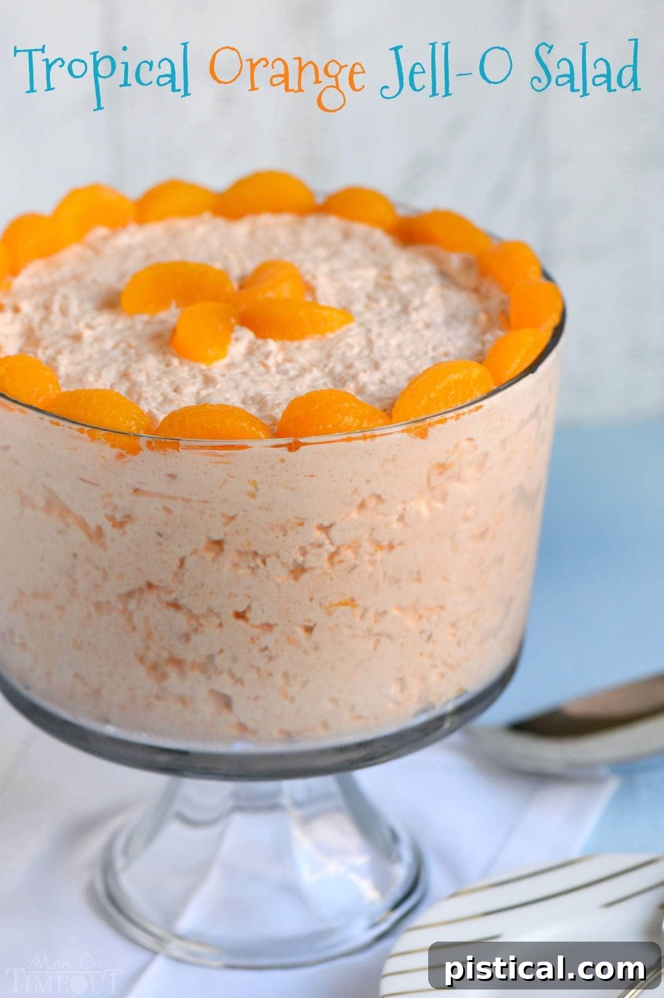 A vibrant Tropical Orange Jello Salad in a glass bowl, garnished with fresh orange slices and mint, ready to be served at a summer party.