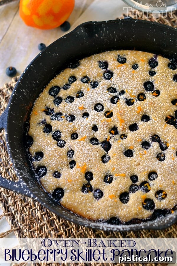 Golden Blueberry Skillet Pancake 6 A perfectly portioned slice of Oven-Baked Blueberry Skillet Pancake, garnished with powdered sugar and orange zest, highlighting its fluffy texture and juicy blueberries. | MomOnTimeout.com #breakfast #blueberries #pancakes