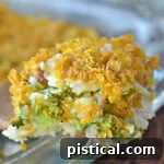 A scoop of Cheesy Chicken Broccoli Rice Casserole being served from a baking dish with a wooden spoon, highlighting its creamy texture.