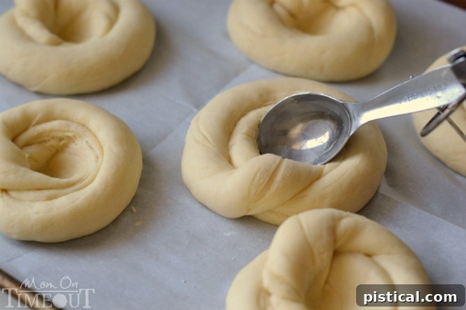 Partially baked sweet rolls arranged on a baking sheet, showing the spiral dough and the rich chocolate hazelnut filling nestled in the center.