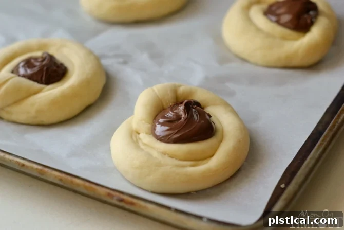 Golden sweet rolls with a visible chocolate hazelnut filling, baked to perfection and ready for glazing.