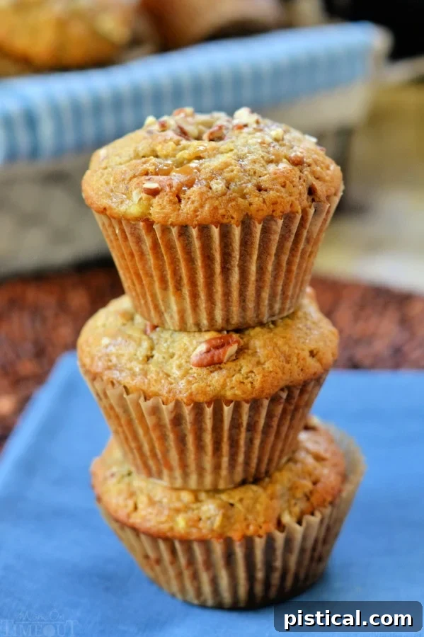 Decadent Caramel Banana Nut Muffins 4 Three perfectly baked caramel banana nut muffins, stacked neatly on a vibrant blue napkin, showcasing their golden tops and tender texture.
