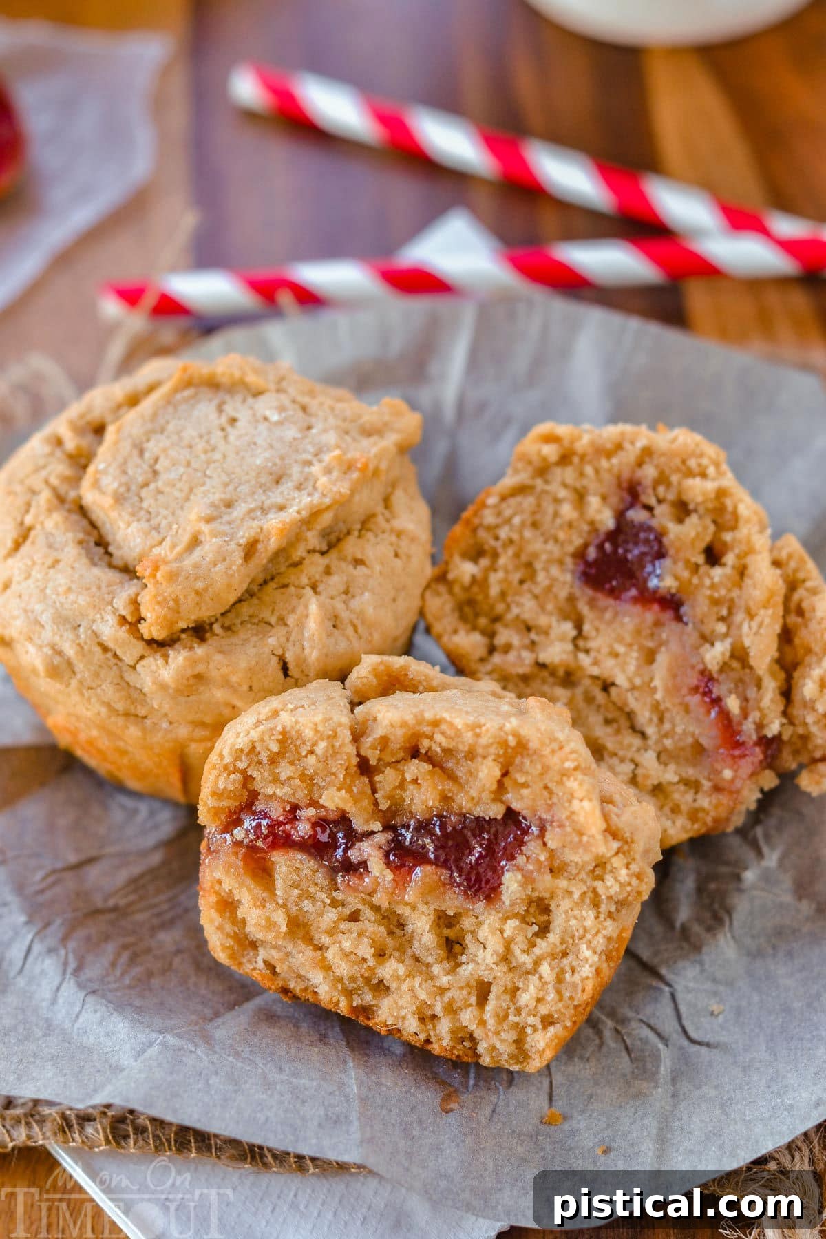PBJ Muffins 6 Two peanut butter and jelly muffins on a piece of parchment. One muffin has been split in half to reveal the jelly center.