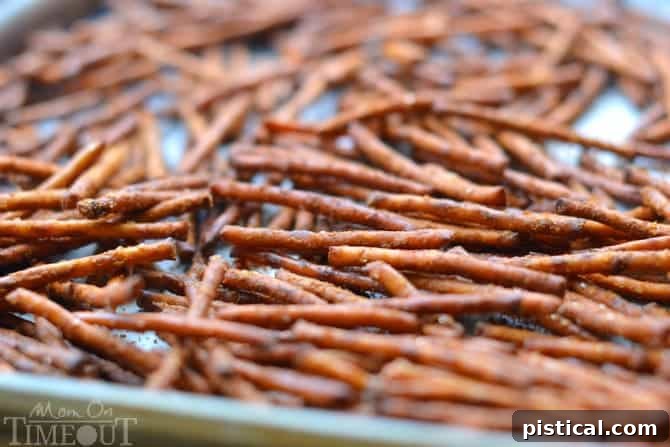 Assortment of spicy Buffalo Wing Pretzel Sticks spread out on a baking sheet, glistening with seasoning.