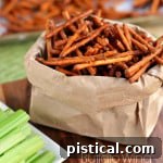 A small bowl of Buffalo Wing Pretzel Sticks, garnished with celery and blue cheese dressing.
