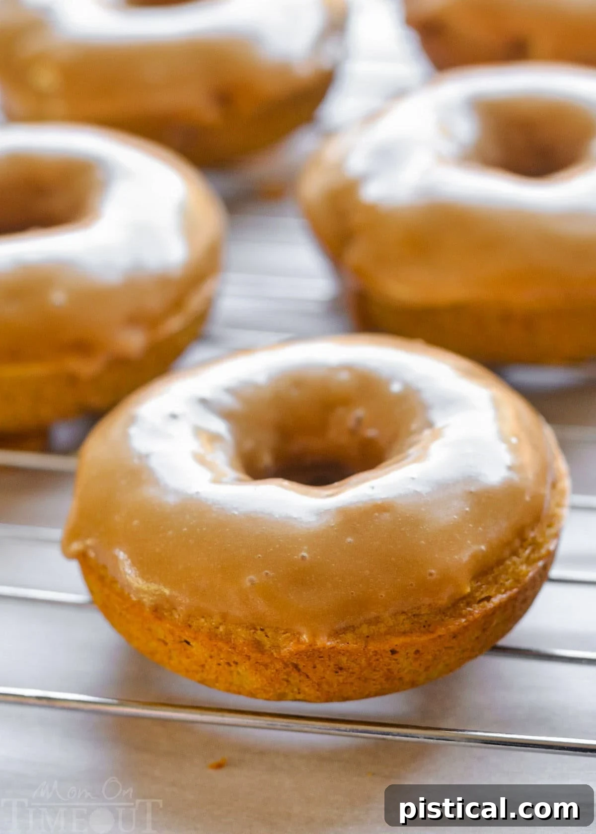 Close-up view of maple glazed pumpkin spice baked cake donuts neatly arranged on a wire cooling rack, showcasing their perfect texture and shiny glaze.