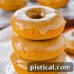 Front view of three baked pumpkin donuts stacked on a cupcake stand.