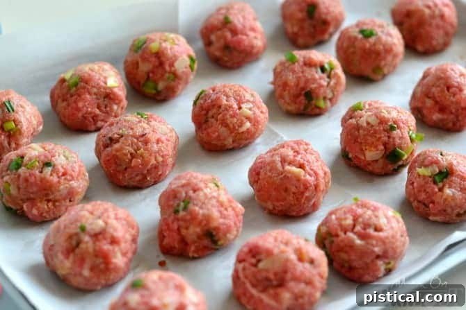 Sticky Teriyaki Meatball Bites 4 Teriyaki Meatballs ready to be baked in the oven on a parchment-lined baking sheet for a perfect cook.