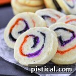 Halloween Sugar Cookies made with orange, black and purple sugar rolleed into a spiral. A stack of cookies in the back and five cookies fanned out in the front to showcase the neat spiral design.