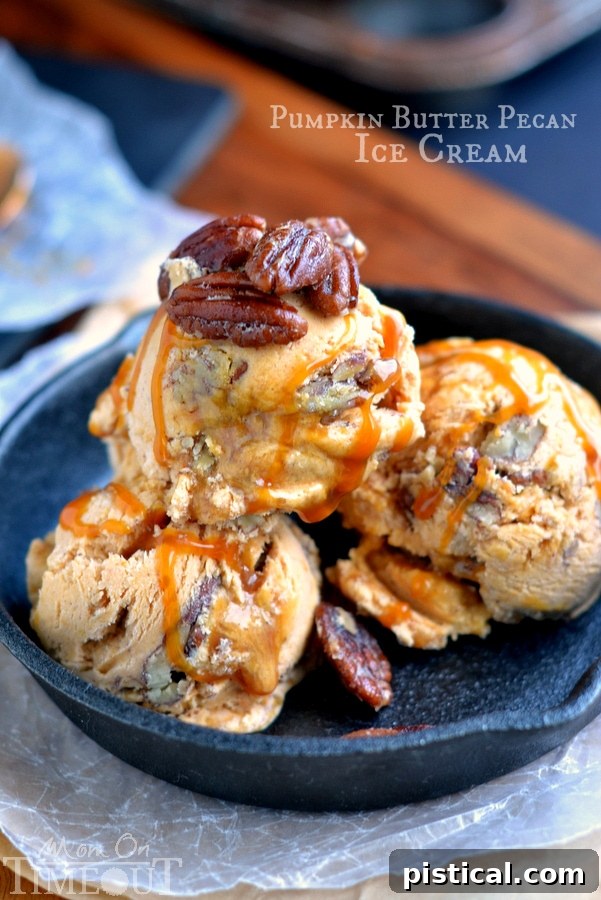 Three scoops of Pumpkin Butter Pecan Ice Cream in a clear bowl, drizzled with caramel and topped with whole pecans