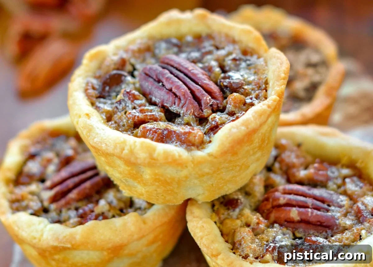 A close-up view of a single mini pecan pie, showcasing its perfect golden-brown crust, rich filling, and a crowning pecan half, emphasizing its irresistible appeal.