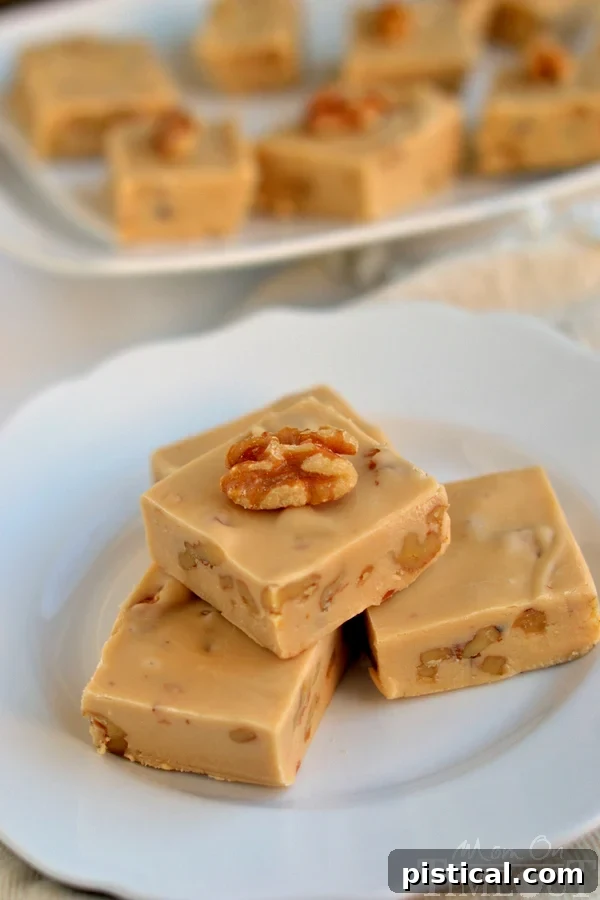 Maple Nut Bliss 4 A close-up shot of a perfectly cut square of Creamy Maple Nut Fudge, topped with additional toasted walnuts, showing its inviting texture.