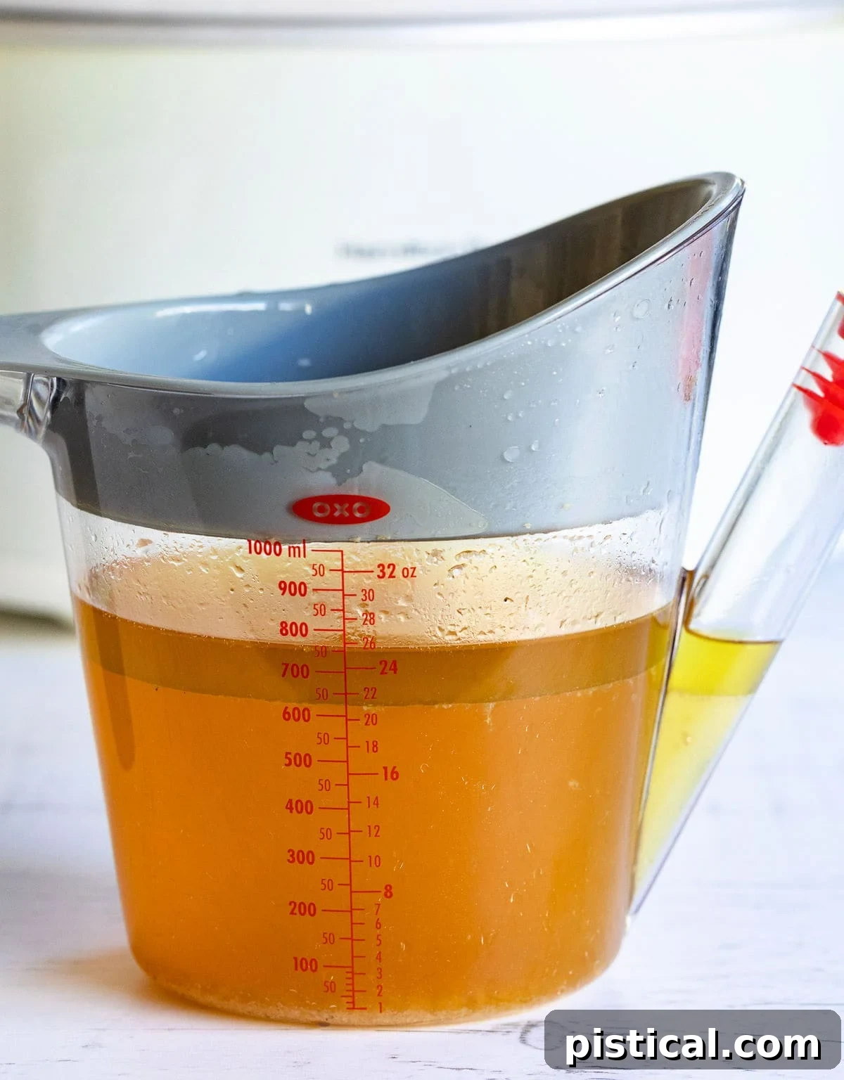 Secrets to Irresistible Turkey Gravy 4 A clear gravy fat separator clearly illustrating how the fat naturally rises to the top, forming a distinct layer above the flavorful turkey drippings, which settle at the bottom.
