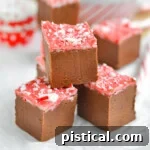 four pieces of peppermint mocha fudge stacked into a pyramid sitting on white parchment paper.