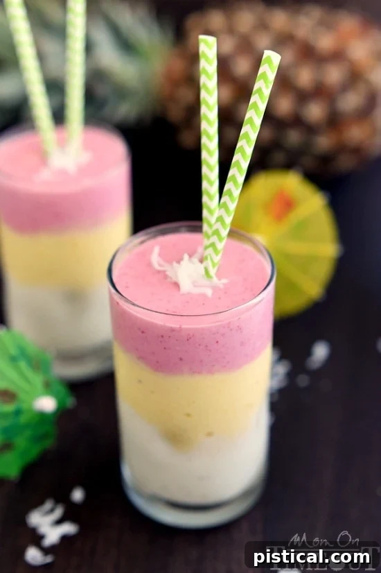 Two hands holding tall glasses of Tropical Sunrise Smoothies, ready to be enjoyed.