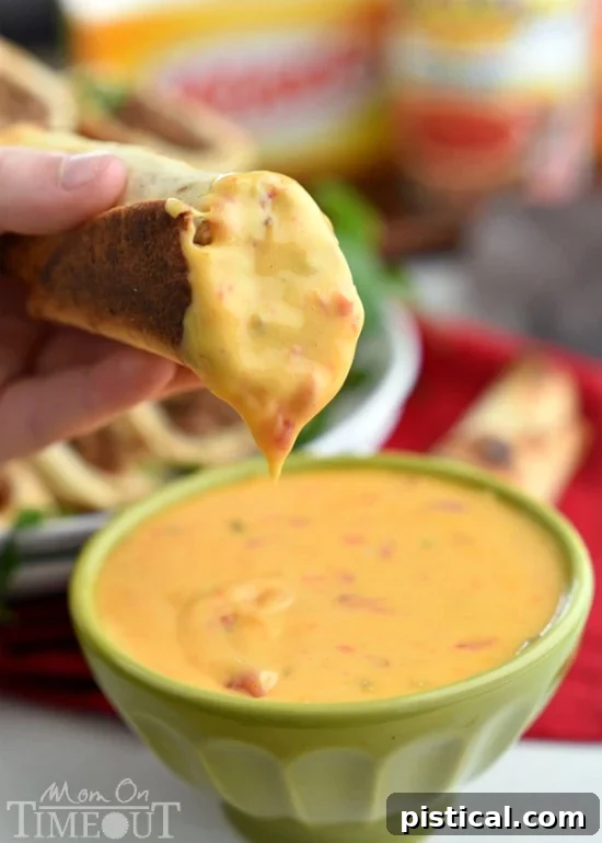 A vibrant bowl of creamy queso dip, made with Ro*Tel and Velveeta, ready for dipping, accompanied by baked flautas.