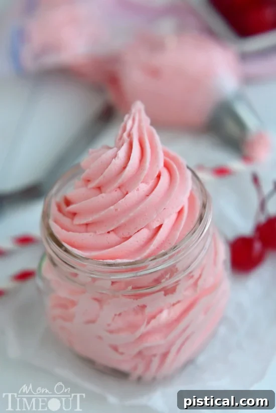 A close-up shot of a spoon dipping into a jar of pink Maraschino Cherry Frosting, showing its creamy and tempting texture.