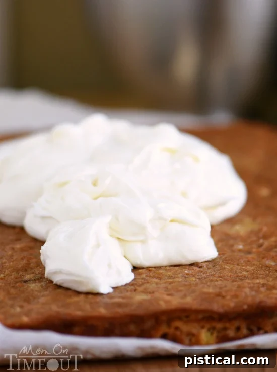 Cream Cheese Frosting being spread generously on cooled Carrot Cake Bars, showcasing a thick layer of deliciousness.