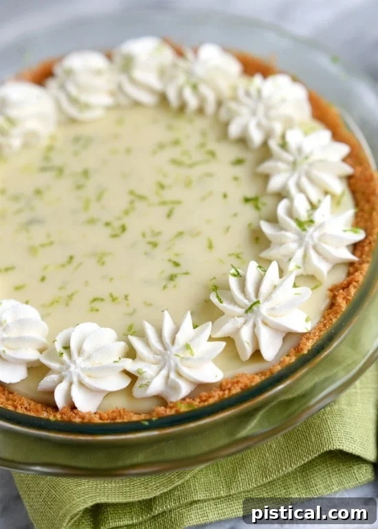 Key Lime Pie with Whipped Cream Topping A close-up of Key Lime Pie, beautifully garnished with a generous swirl of fluffy homemade whipped cream and fresh lime zest, ready to be served.