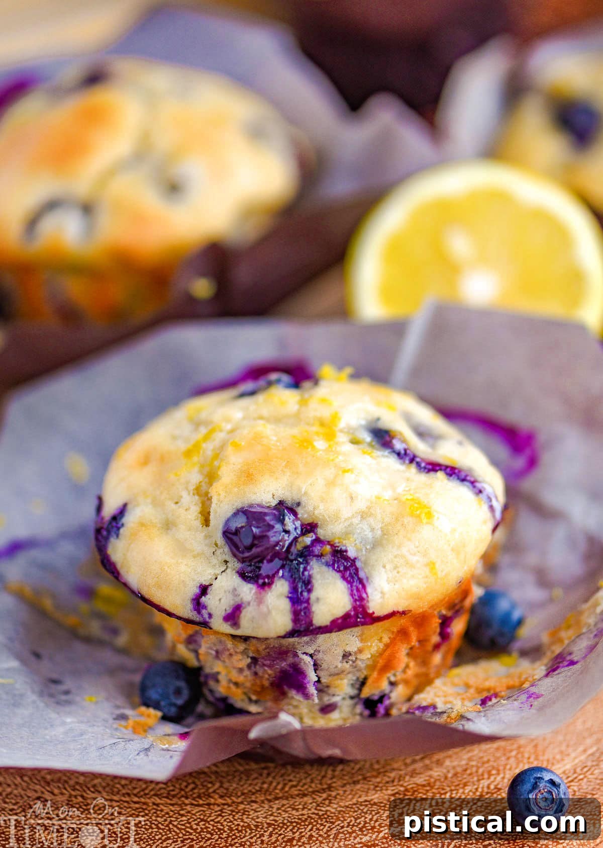 Zesty Lemon Blueberry Muffins with Cream Cheese Swirl 7 Blueberry Lemon Cream Cheese Muffins topped with a lemon glaze resting on parchment liner.