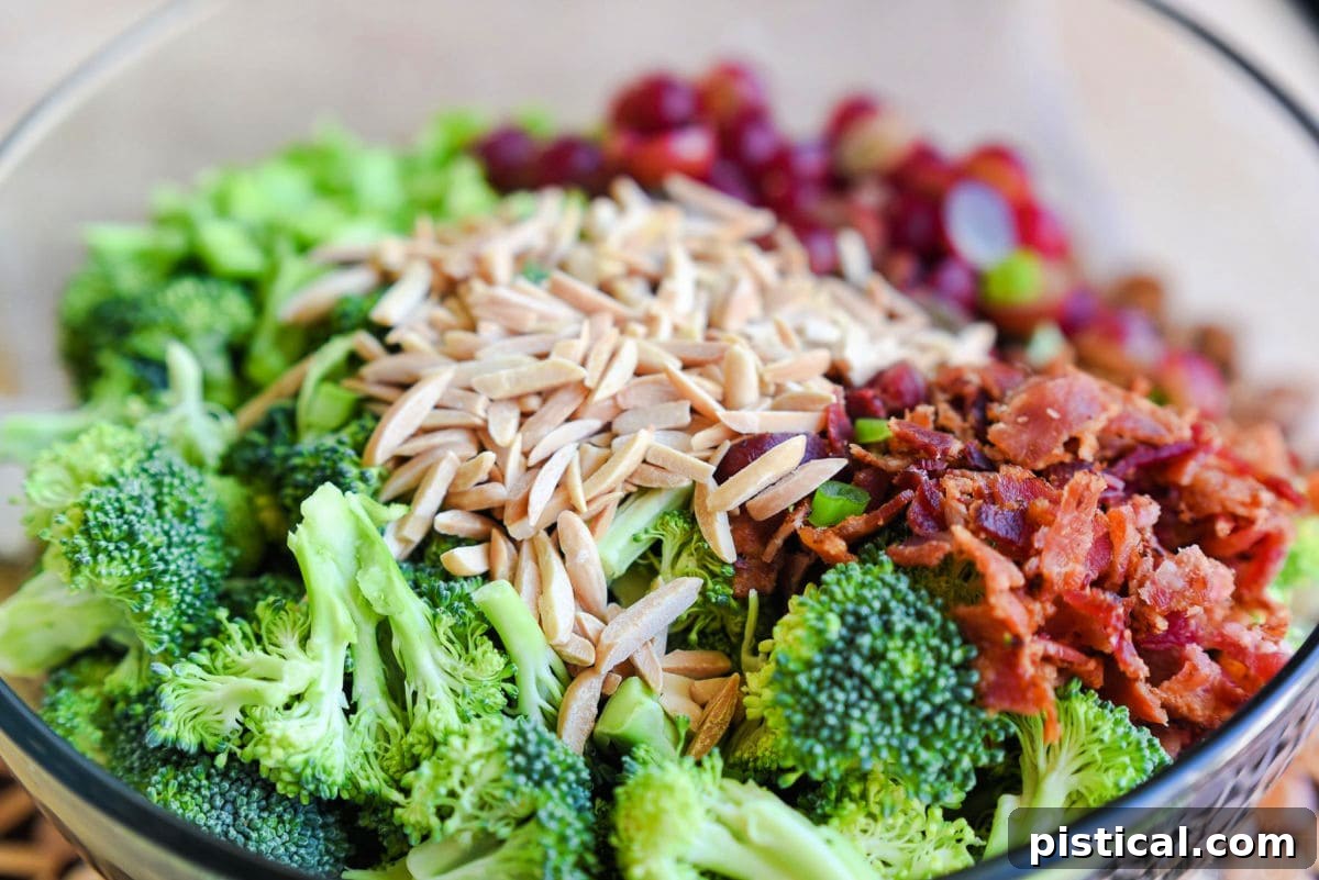 clear glass bowl filled with broccoli salad ingredients ready to be tossed together with the broccoli salad dressing.