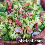 dark brown wood bowl filled with freshly prepare broccoli salad recipe made with grapes and bacon.