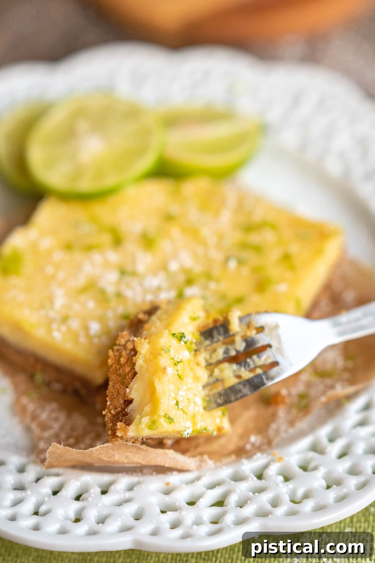 Zesty Key Lime Squares 3 A single Key Lime Pie Bar resting on a pristine white plate, with a fork poised to take a bite from its perfectly set, creamy filling and golden graham cracker crust.