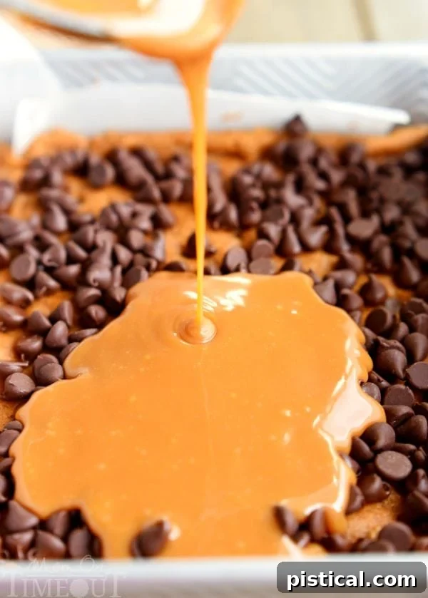 Warm caramel sauce being drizzled over a layer of semi-sweet chocolate chips, prepared for baking in a Carmelitas bar recipe.