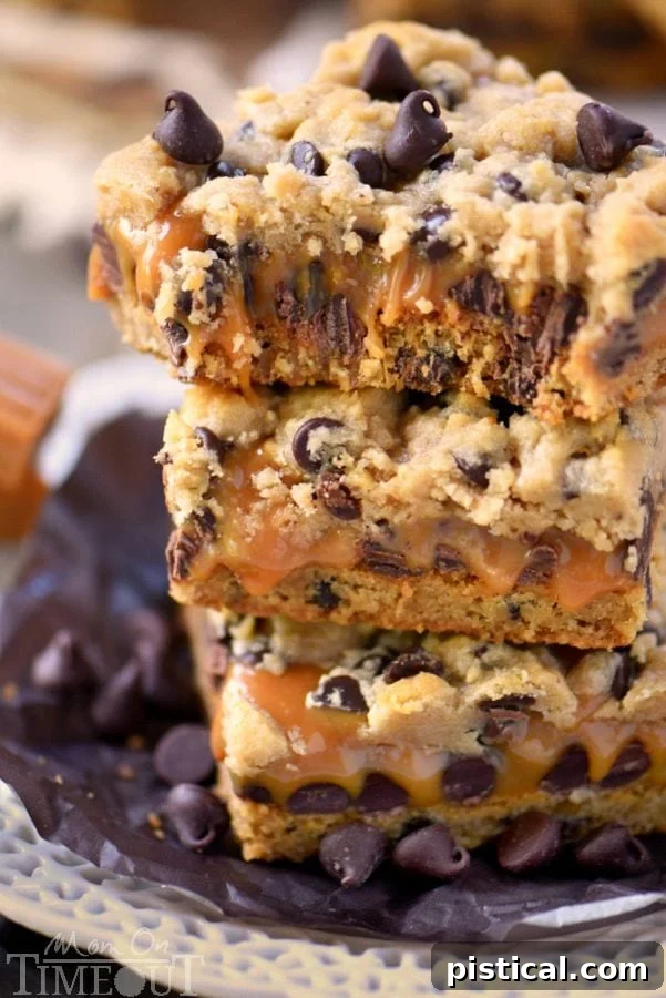 A sliced Carmelita bar with a bite taken, revealing the luscious layers of chocolate chip cookie, gooey caramel, and melted chocolate.