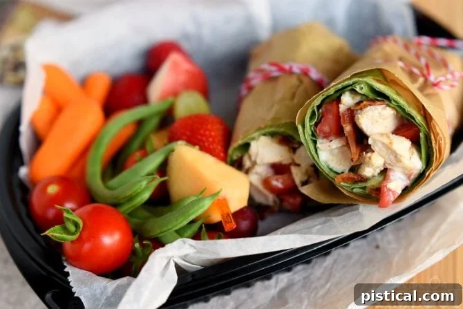 Assortment of healthy road trip snacks including BLT Chicken Caesar Salad Wraps, fruit kabobs, and fresh vegetables like carrots, cherry tomatoes, and green beans. | MomOnTimeout.com | #recipe #ad