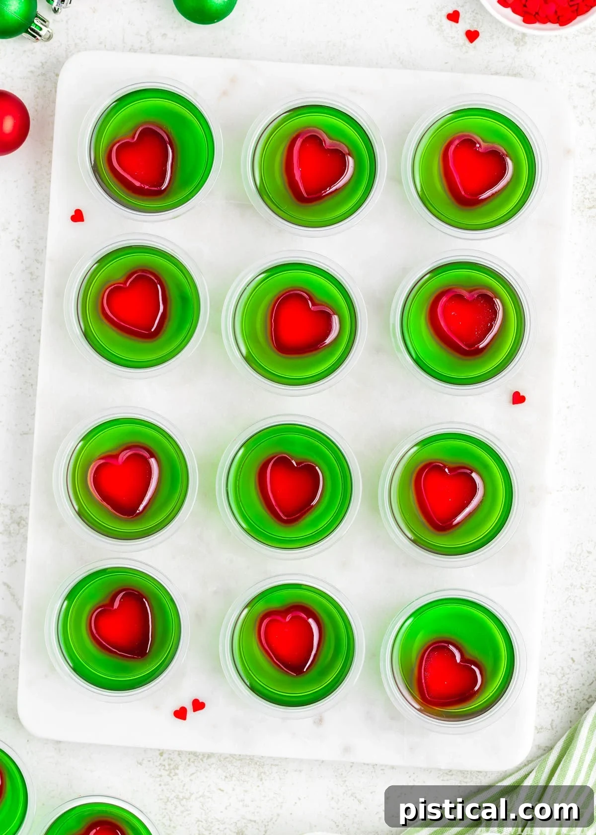 A top down view of Grinch Jello Shots lined up on a marble cutting board.
