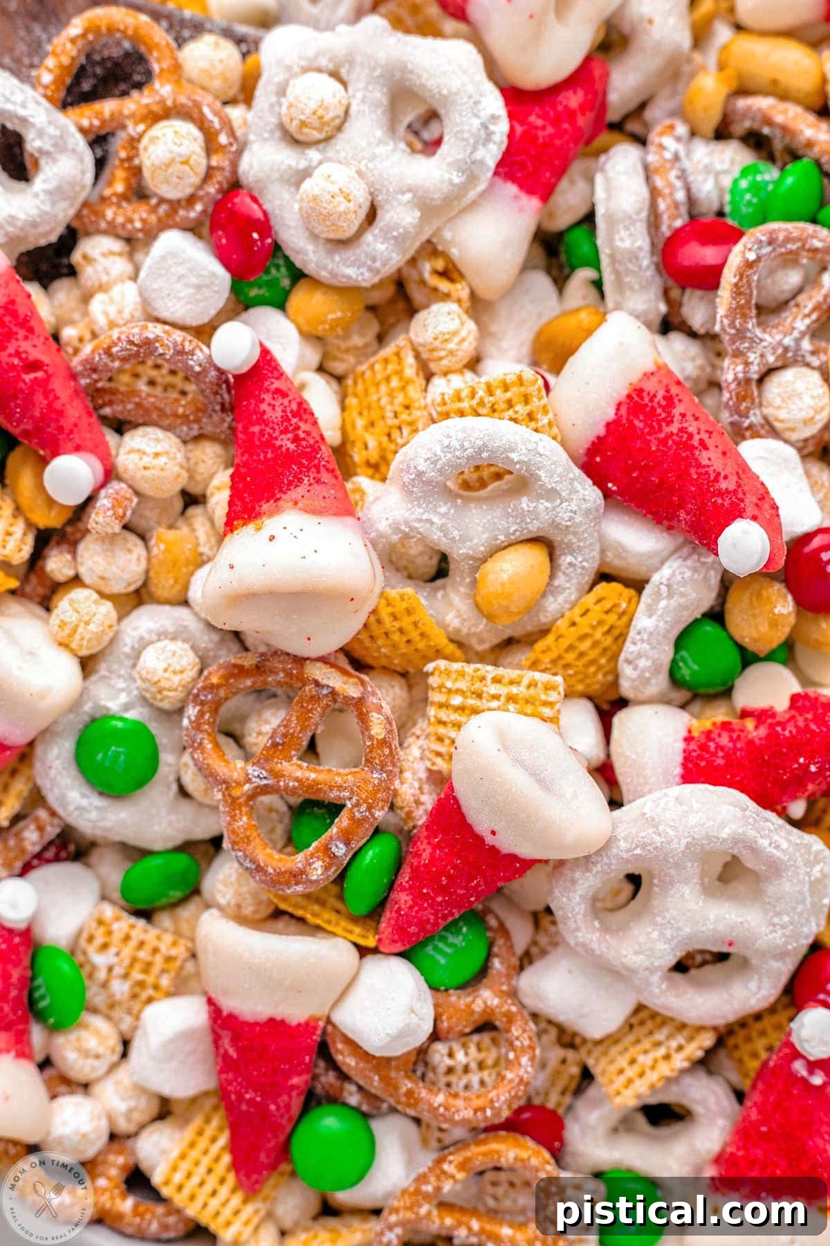 Close-up shot of a vibrant Santa's Christmas Snack Mix, showcasing crunchy cereal, salty pretzels, festive M&M's, and adorable homemade Santa Hats. Perfect for holiday parties or gifting.