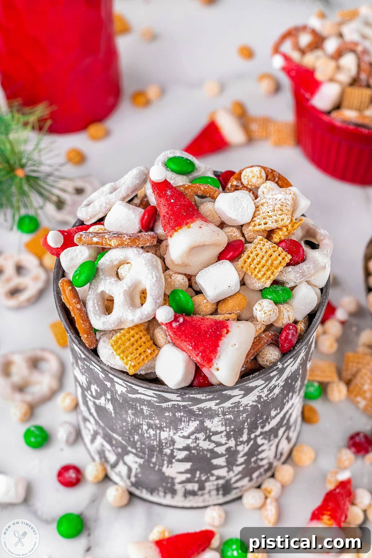 A charming metal bucket overflowing with Santa's Snack Mix, featuring a delightful assortment of cereals, pretzels, and colorful candies.
