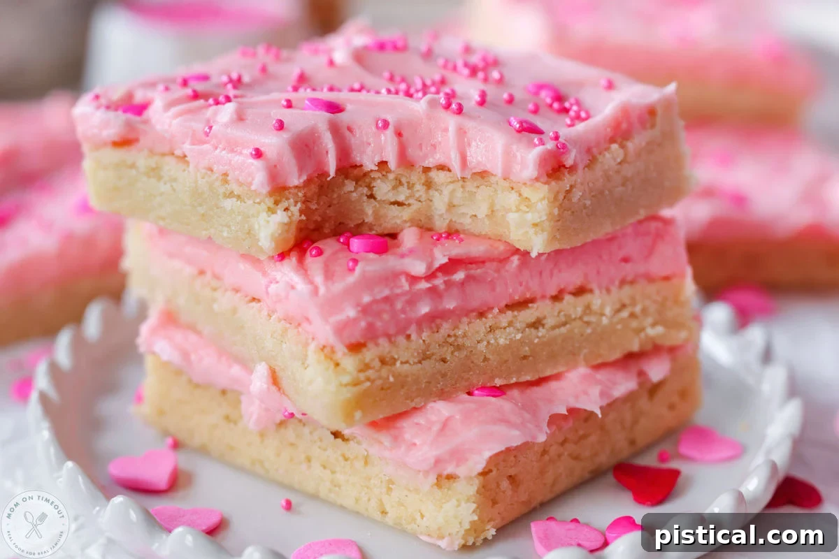Close up shot of valentines day cookie bars stacked three high on round white scalloped edge plate. Top bar has a bite taken.