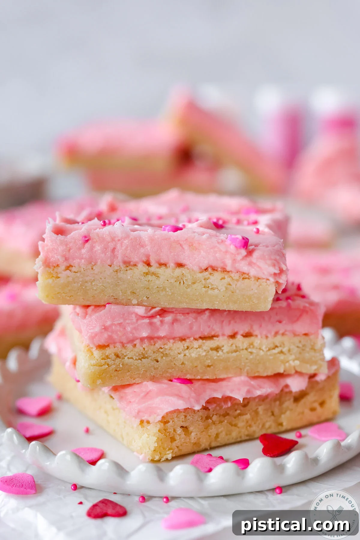 Three sugar cookie bars decorated for valentine's day stacked on white plate.