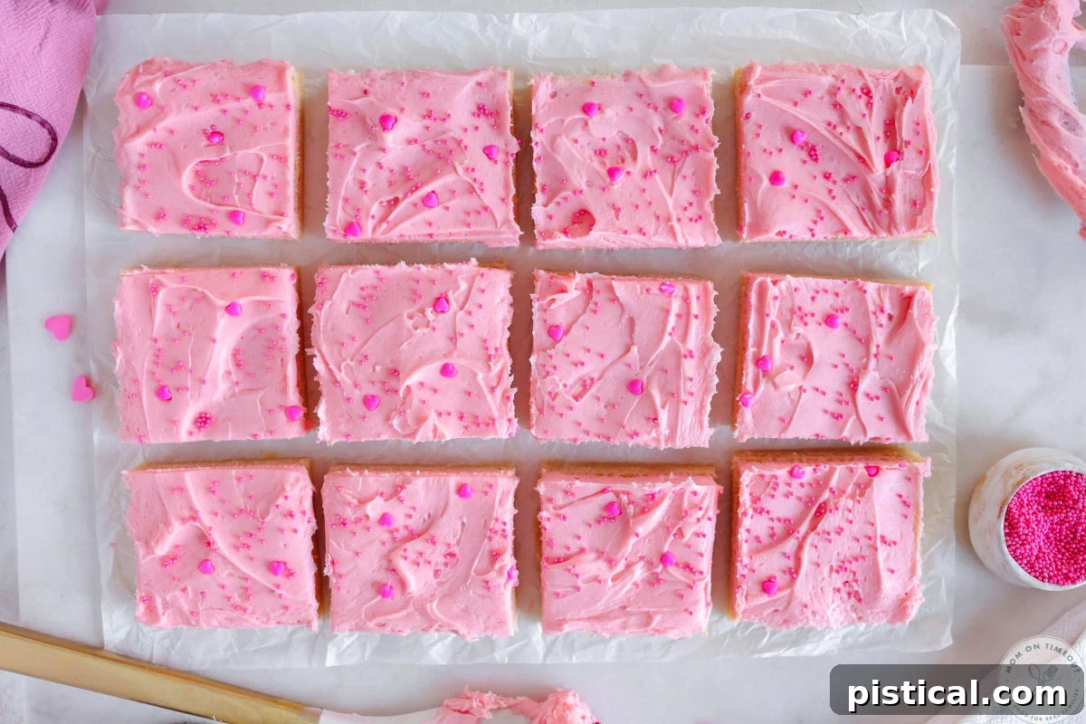 Wide shot of sugar cookie bars cut into squares on parchment paper.