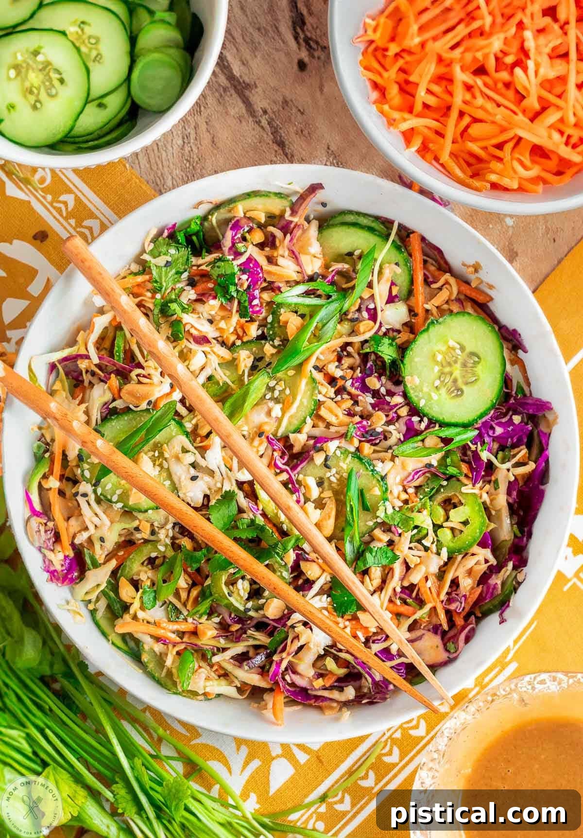 Overhead shot of large white bowl with summer thai salad that has been tossed with peanut dressing. Two chopsticks are laid on top of the bowl.