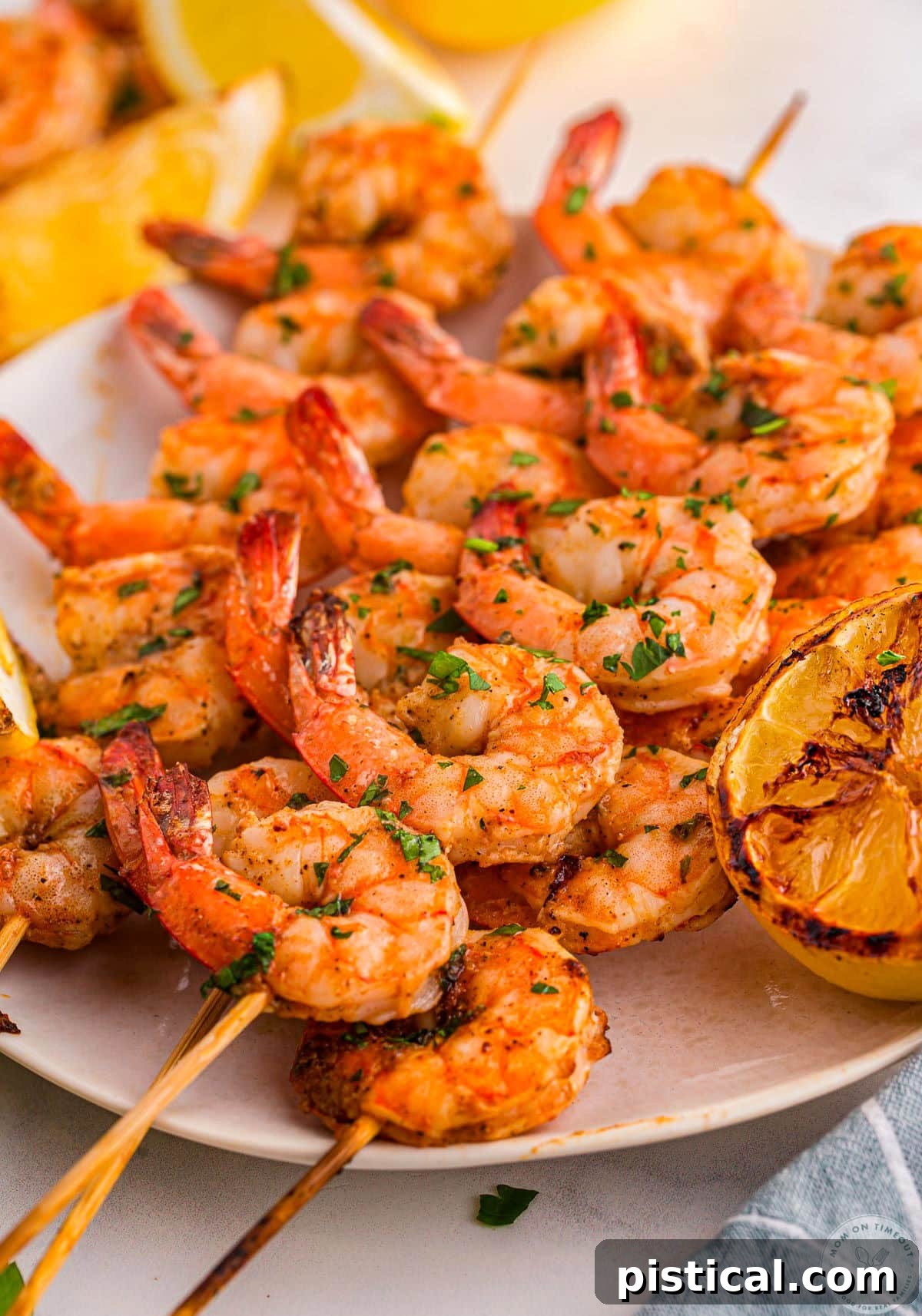 Plate topped with cajun shrimp on skewers ready to be enjoyed. Lemon wedges can be seen in the background.