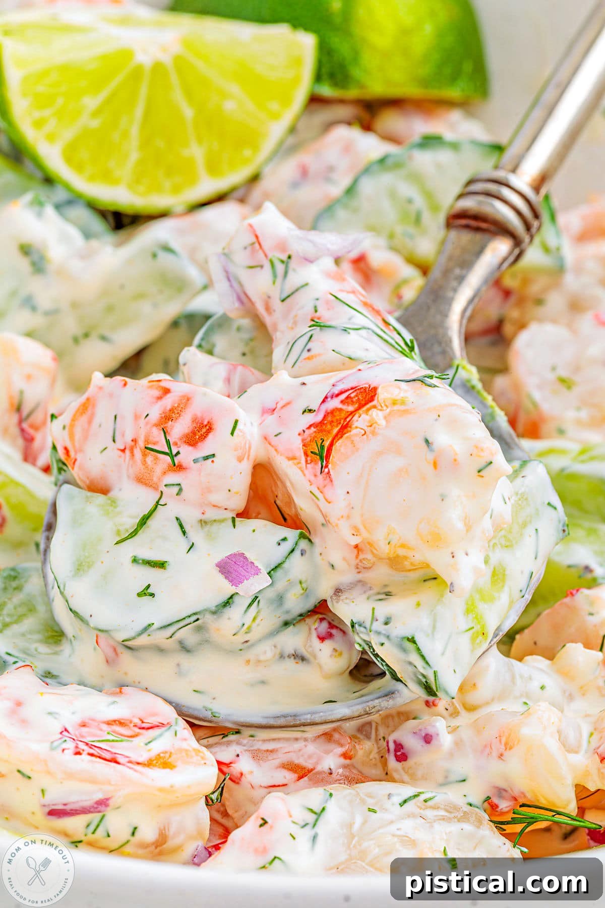 Large serving spoon with a scoop of cucumber shrimp salad being lifted away from the serving bowl.