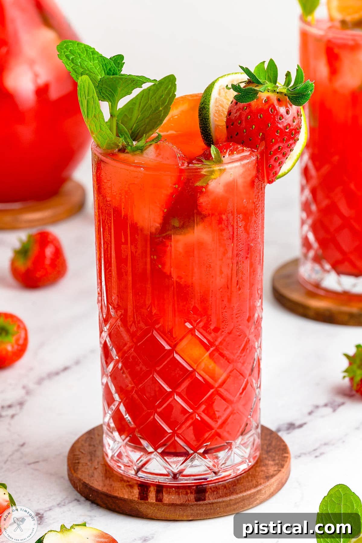 Fresh Strawberry Mojito Recipe: Sparkling Summer Cocktail 4 Close up of strawberry mojito in a tall glass. Garnished with mint and strawberries.